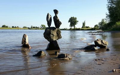 Stack of rocks on lakeshore against clear sky