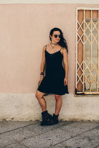 Full length portrait of woman standing against wall