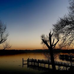 Silhouette pier on lake against clear sky during sunset