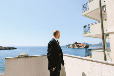 Full length of man looking at sea against clear sky