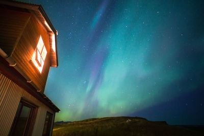 Low angle view house against aurora borealis at night
