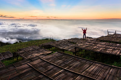 Man standing on wood against sky during sunset