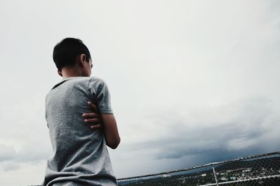 Side view of boy standing against sky