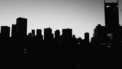 Silhouette cityscape against sky