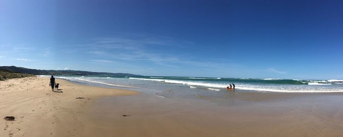 People at beach against blue sky