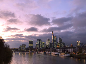 Buildings by river against sky in city