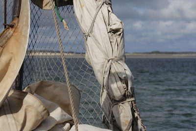 Net on boat by sea against cloudy sky