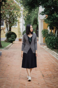 Portrait of young woman standing against trees