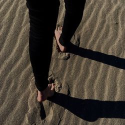 Low section of woman walking on sand