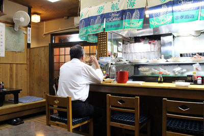 Rear view of man working on table at restaurant