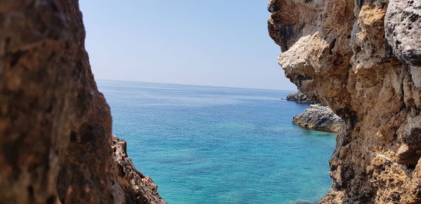 Rock formations in sea against clear blue sky