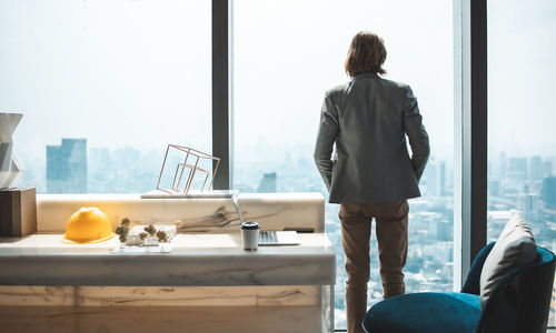 Rear view of woman standing by glass window