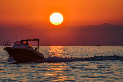 Boat in sea against sky during sunset