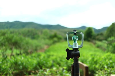 Coin-operated binoculars on field against sky