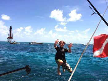 Boy jumping over sea against sky