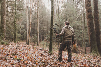 Rear view of man with equipment standing in forest