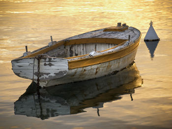 Boat moored on beach against sky during sunset