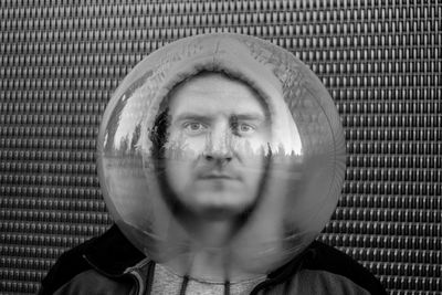 Portrait of man wearing spherical shape glass against wall