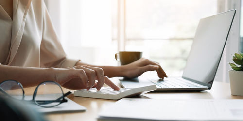 Midsection of man using laptop on table
