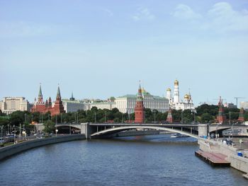 Bridge over river amidst buildings in city against sky