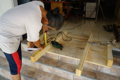 Side view of man carpenter cutting wood with saw or no safety at work