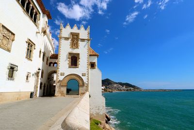 Buildings by sea against blue sky