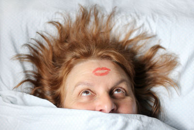 Woman with lipstick mark on head sleeping on bed