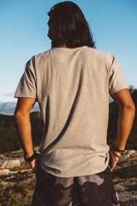 Man from behind hands on pockets outdoors in blue sky day