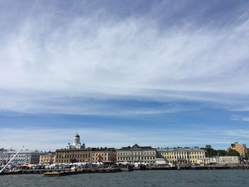 View of buildings by sea against cloudy sky