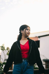 Young woman standing against trees