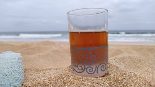 Close-up of drink on glass at beach against sky