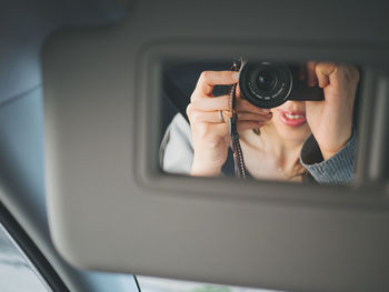 Close-up of woman holding camera in mirror