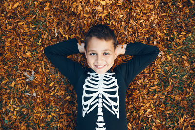 Portrait of happy boy with leaves in autumn