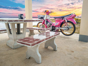 Bicycles on table by road against sky during sunset