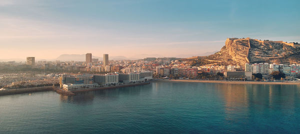 River amidst buildings against sky during sunset