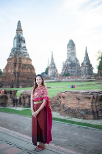 Portrait of woman standing in traditional clothing against temple