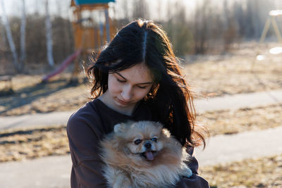 A girl walks with a dog in the park, outdoor recreation with a pet, a portrait with a small puppy