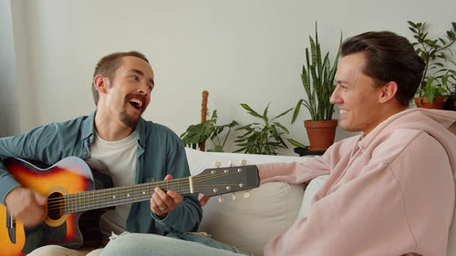 Young man playing guitar with gay partner