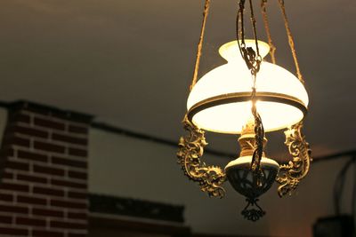 Low angle view of illuminated lighting equipment hanging against ceiling