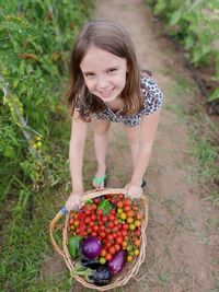 Portrait of young woman picking vegetables in basket