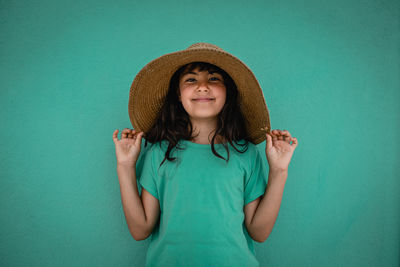 Portrait of young woman wearing hat against wall