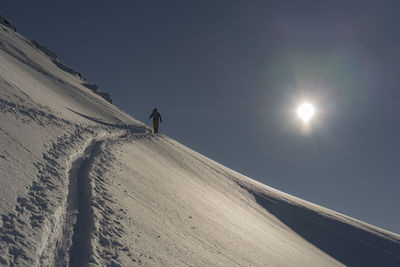 Person on snowcapped mountain against sky during winter