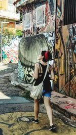 Full length of young woman standing against built structure