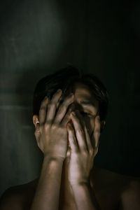 Close-up of woman covering face against wall