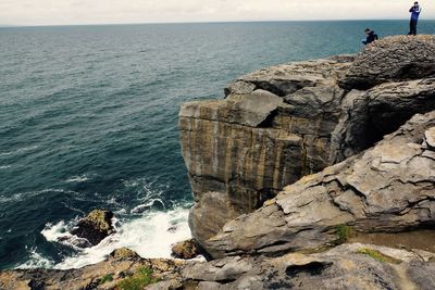 Scenic view of sea by cliff against sky