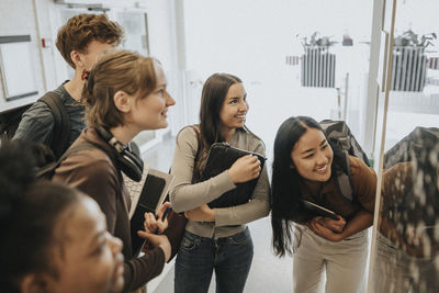 Cheerful multiracial male and female students checking result on bulletin board in university