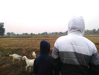 Rear view of men on field against sky