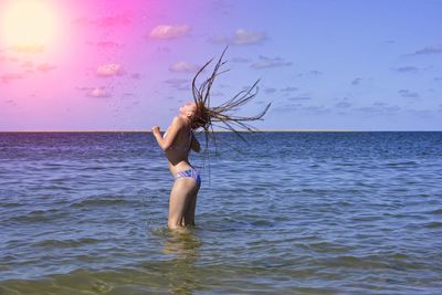 Young woman in sea against sky