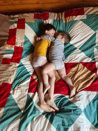 Two kids brothers lie on the bed with a bright bedspread hugging family lifestyle