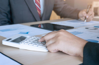 Businesswoman discussing over graphs with colleagues at table